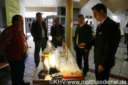 1. Bürgermeister Manfred Ländner lässt sich neueste Produkte von Elektromeister Andreas Kamm erklären.